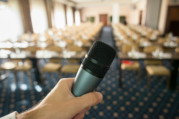 handheld microphone in front of room of chairs