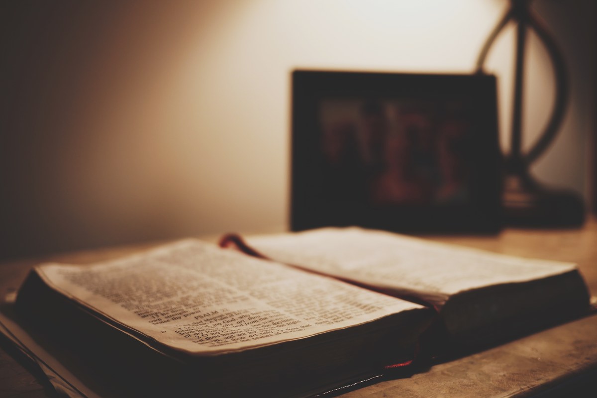Open Bible on a wooden table, turned to Psalm 22, with a red ribbon bookmark.
