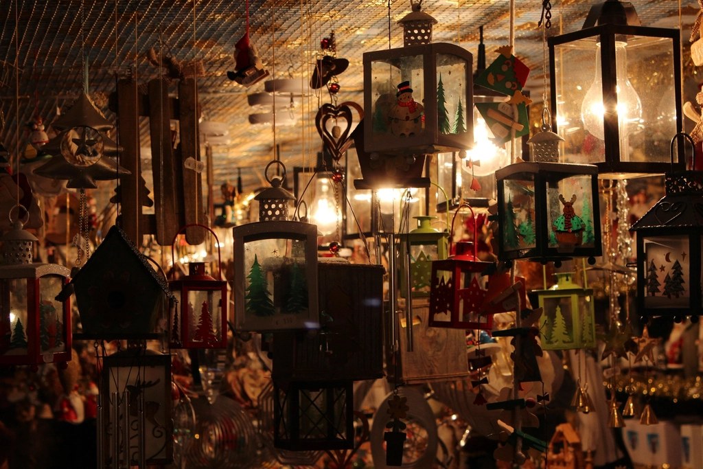 Warmly lit shop interior filled with hanging holiday lanterns and wooden ornaments.