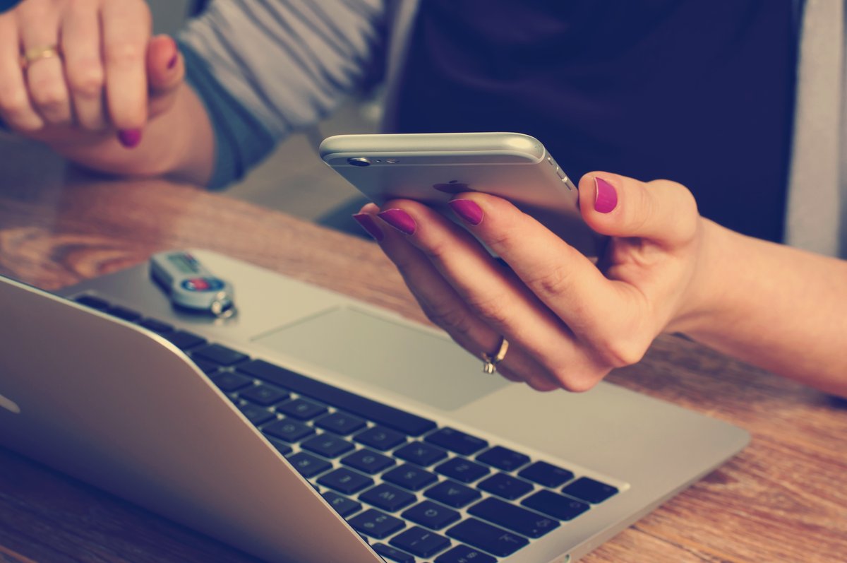 A woman checking her phone while sitting at her laptop