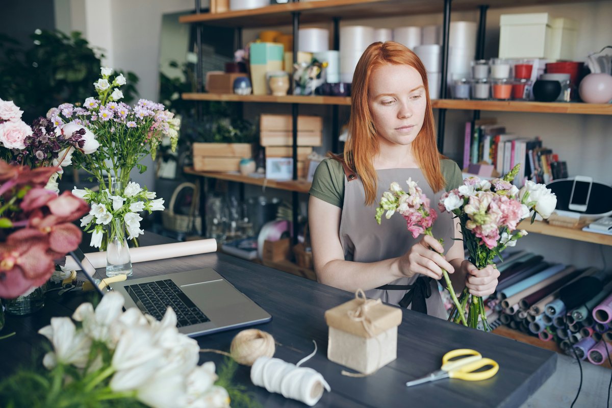 A florist in her flower shop working on a laptop